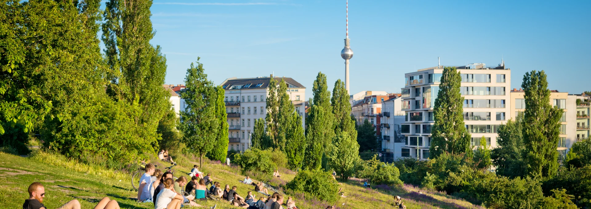 Stadtansicht Berlin mit Park und Menschen im Vordergrund und Fernsehtürm im Hintergrund Stadtansicht Berlin mit Park und Menschen im Vordergrund und Fernsehtürm im Hintergrund