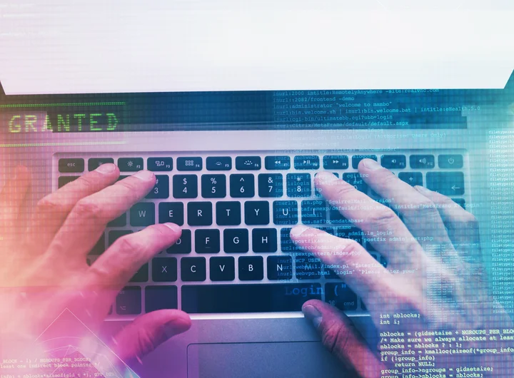 Auf dem Fotos ist ein Laptop mit zwei Händen beim Schreiben auf der Tastatur zu sehen