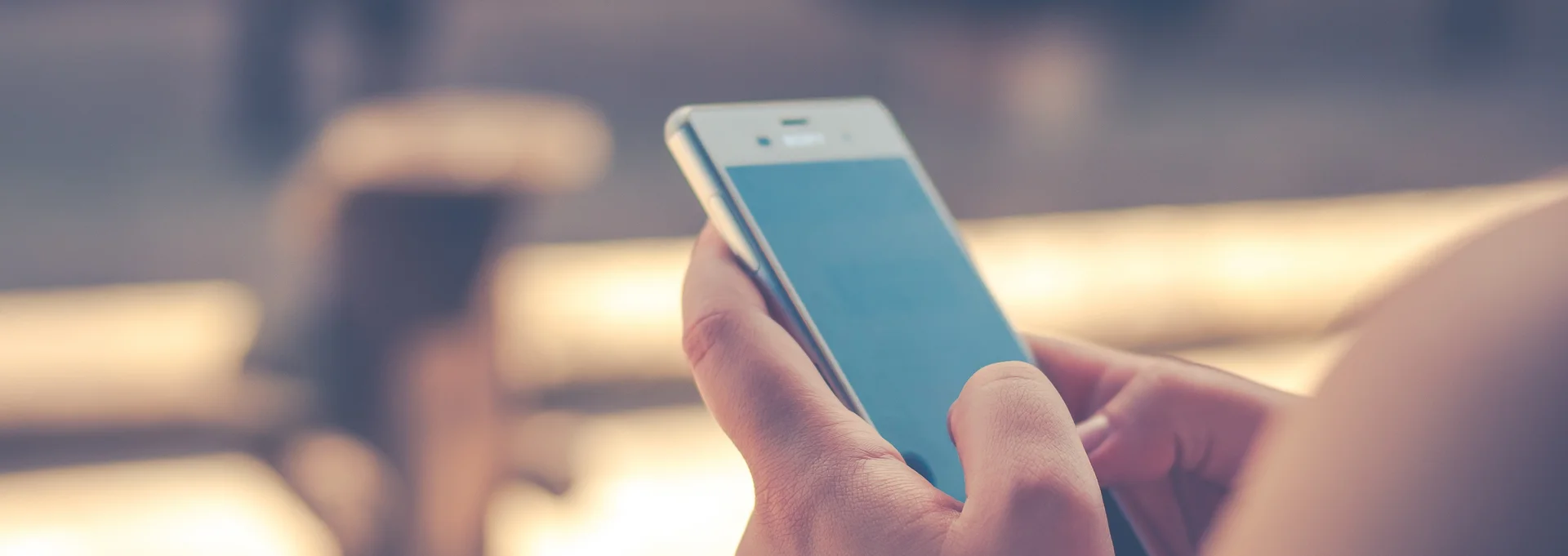 Hilfeportal-Missbrauch Bild zeigt ein Smartphone in der Hand einer Frau, der Hintergrund ist unscharf