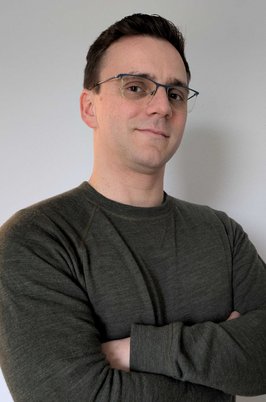 Profilfoto von Max, Mann mit Brille und verschränkten Armen lächelt in die Kamera